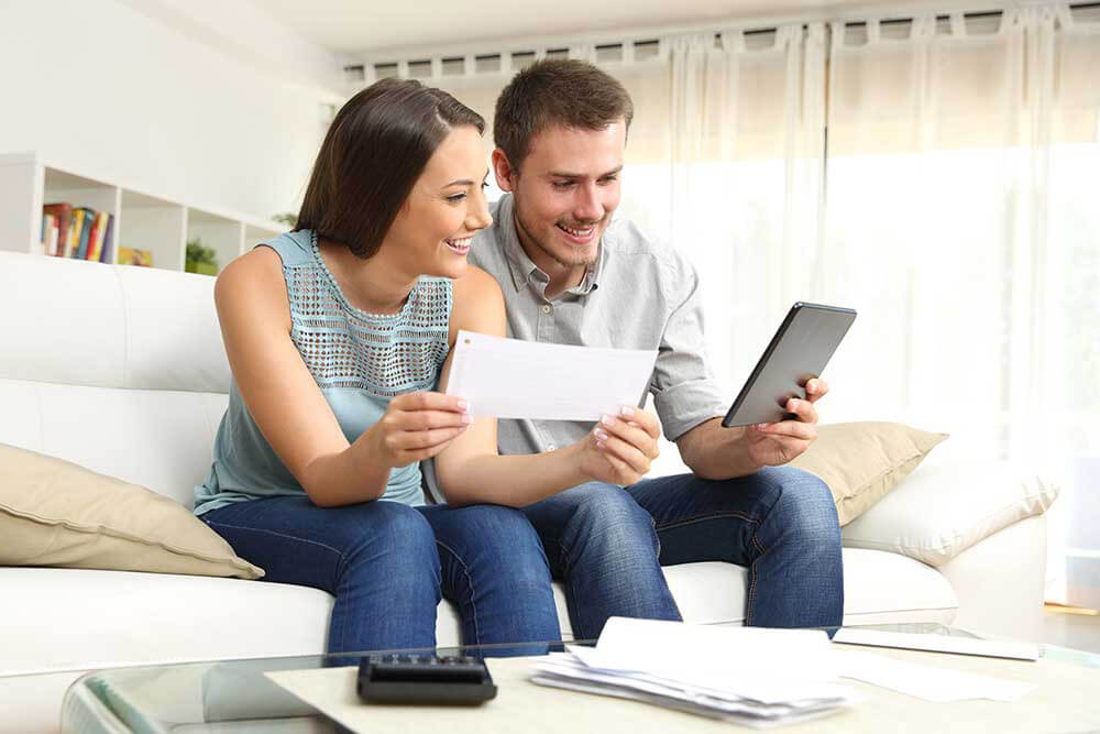 man and woman holding an ipad and a check